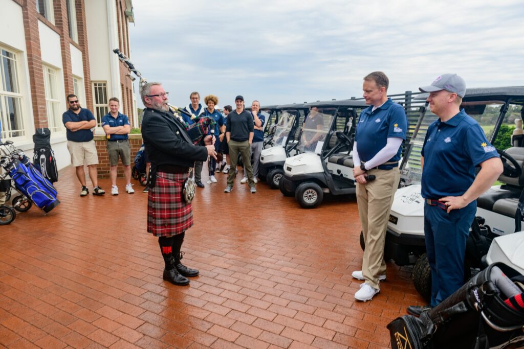 (Foreground) Frank Fraser (Bagpipe Player), Joe Sponholz (LEK Partner), Ian Watt (LEK Partner) – (Background) Tim Stoll (LEK Allocations Manager), David Chalmers (LEK Partner), Nick Holder (LEK Partner, Head of APAC), Eloni Vunakece (Former NRL Roosters Player)